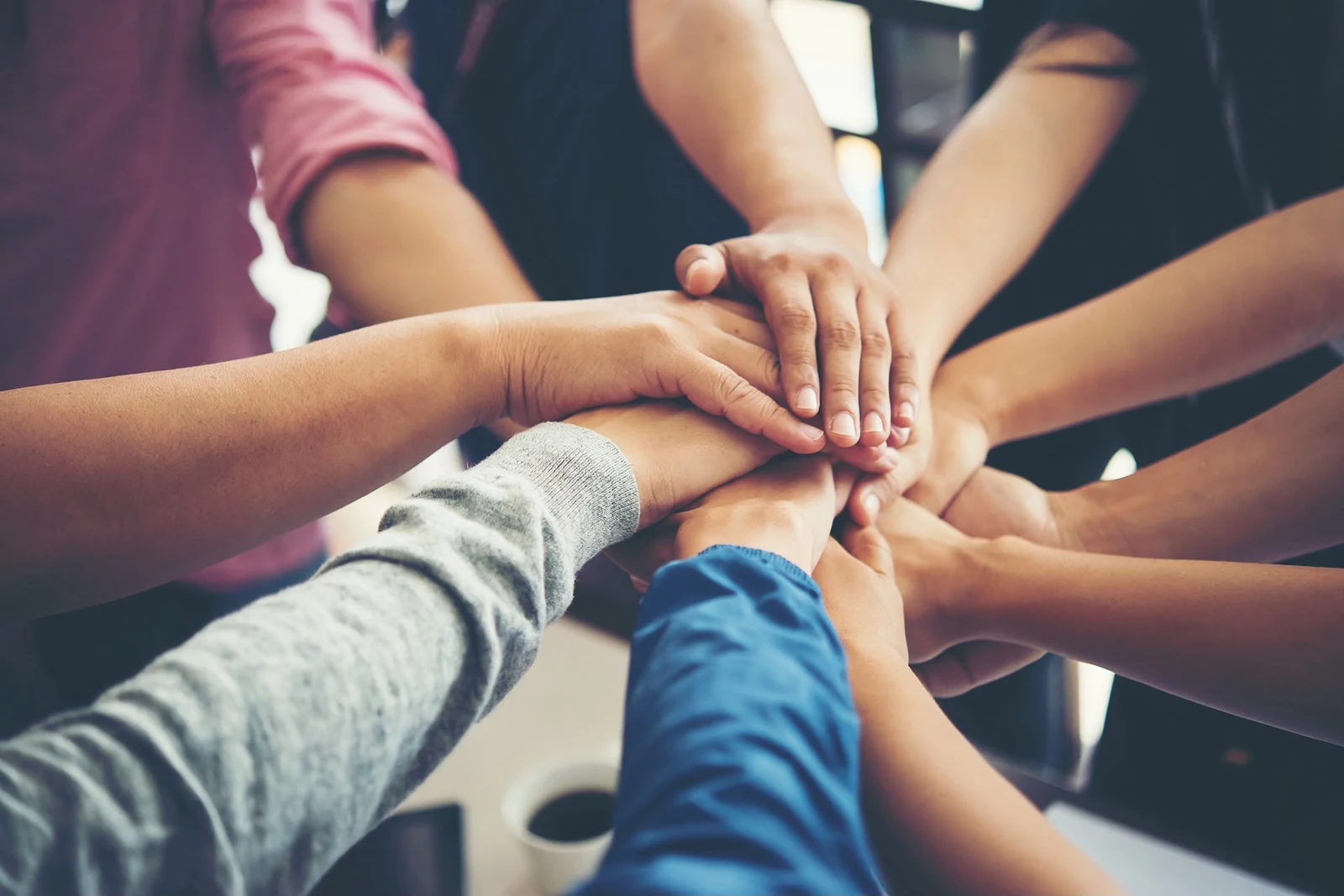 Grupo de compañeros con las manos unidas, símbolo de apoyo mutuo y acompañamiento en la recuperación